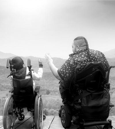 The image is of an older and younger tagata sa'ilimalo in their wheelchairs looking out to the view of the mountains and l